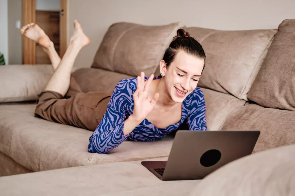 A young woman engaging in a lively video chat session on her laptop, with a friendly smile and a warm, inviting atmosphere.