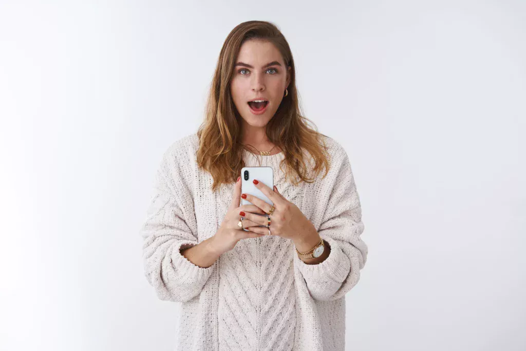 Woman holding a smartphone while reading news about whether Omegle is coming back