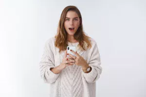 「Omegleが復活するのか」というニュースを読みながら、スマートフォンを手にしている女性